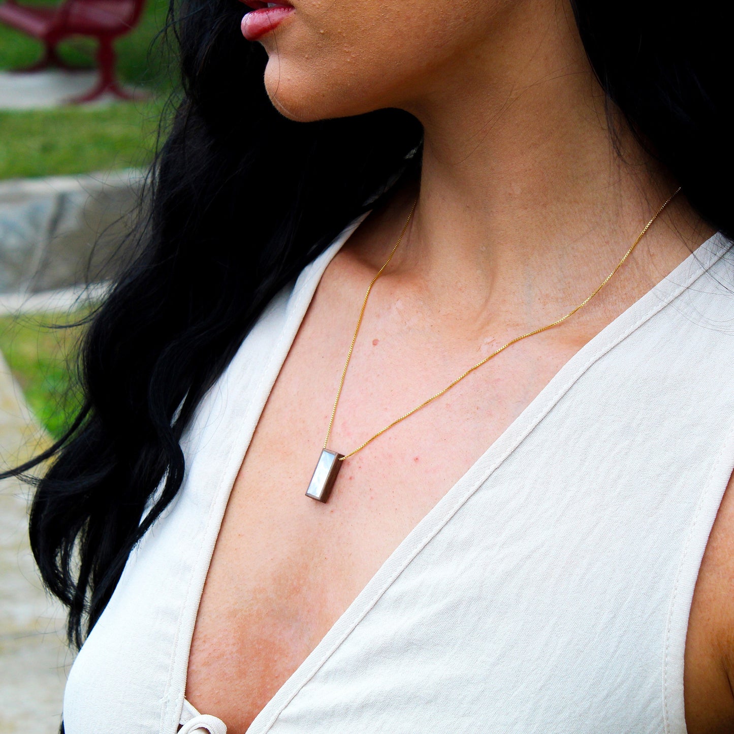 Woman wearing a necklace with a blurred outdoor background