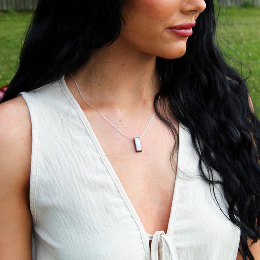 Woman wearing a necklace with a pendant in an outdoor setting