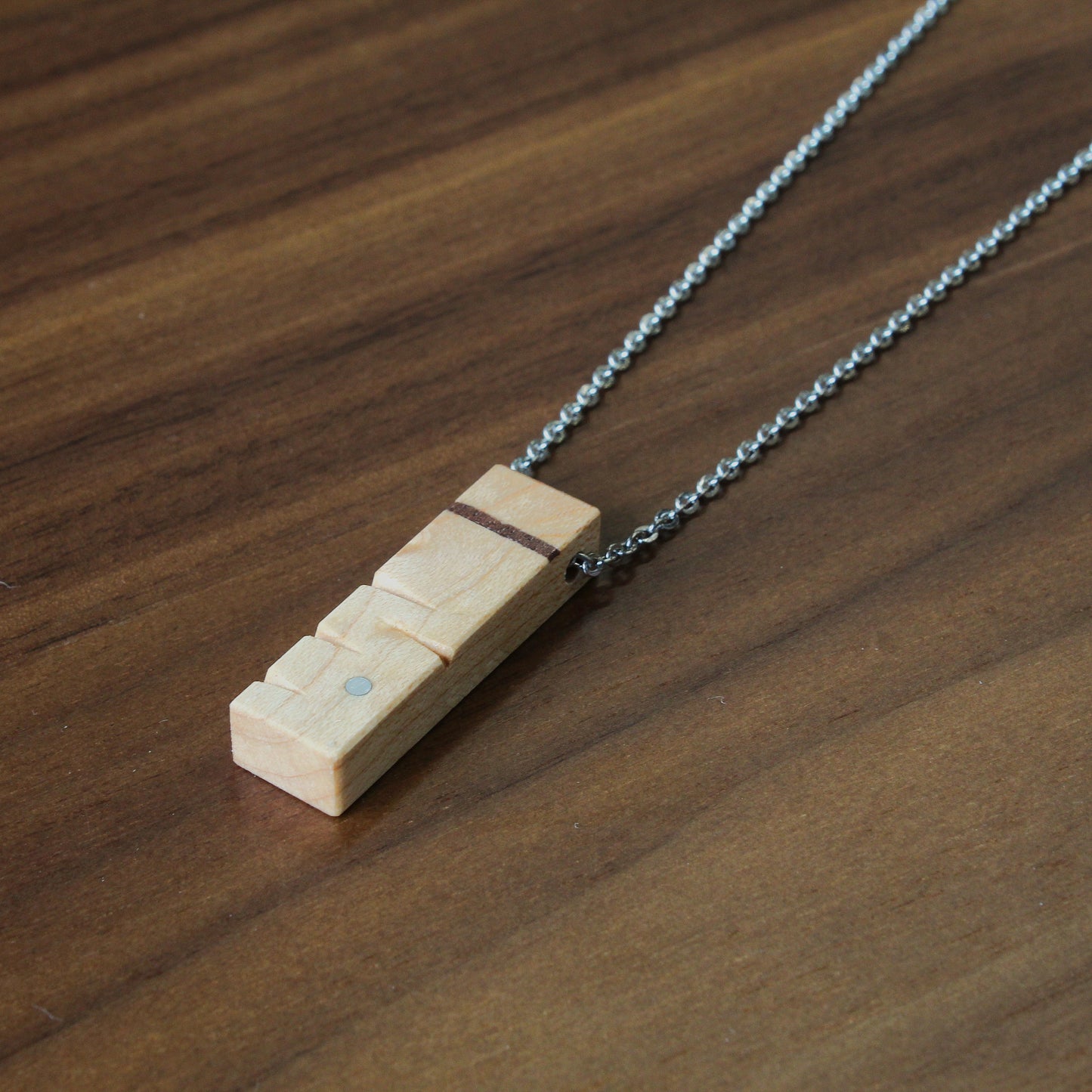 Wooden pendant on a chain lying on a wooden surface