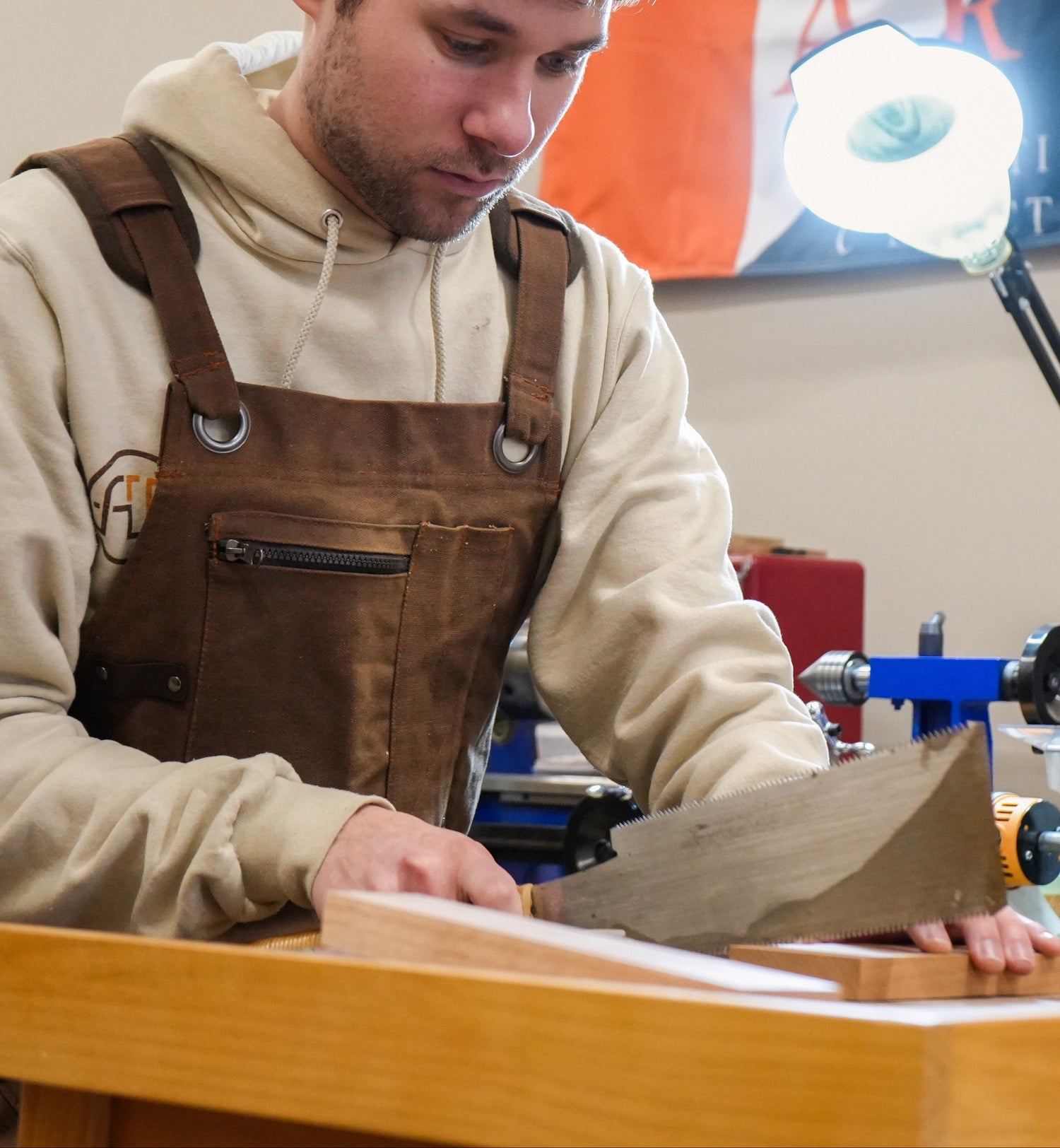 Man in overalls working on a project with a Newport RI flag in the background