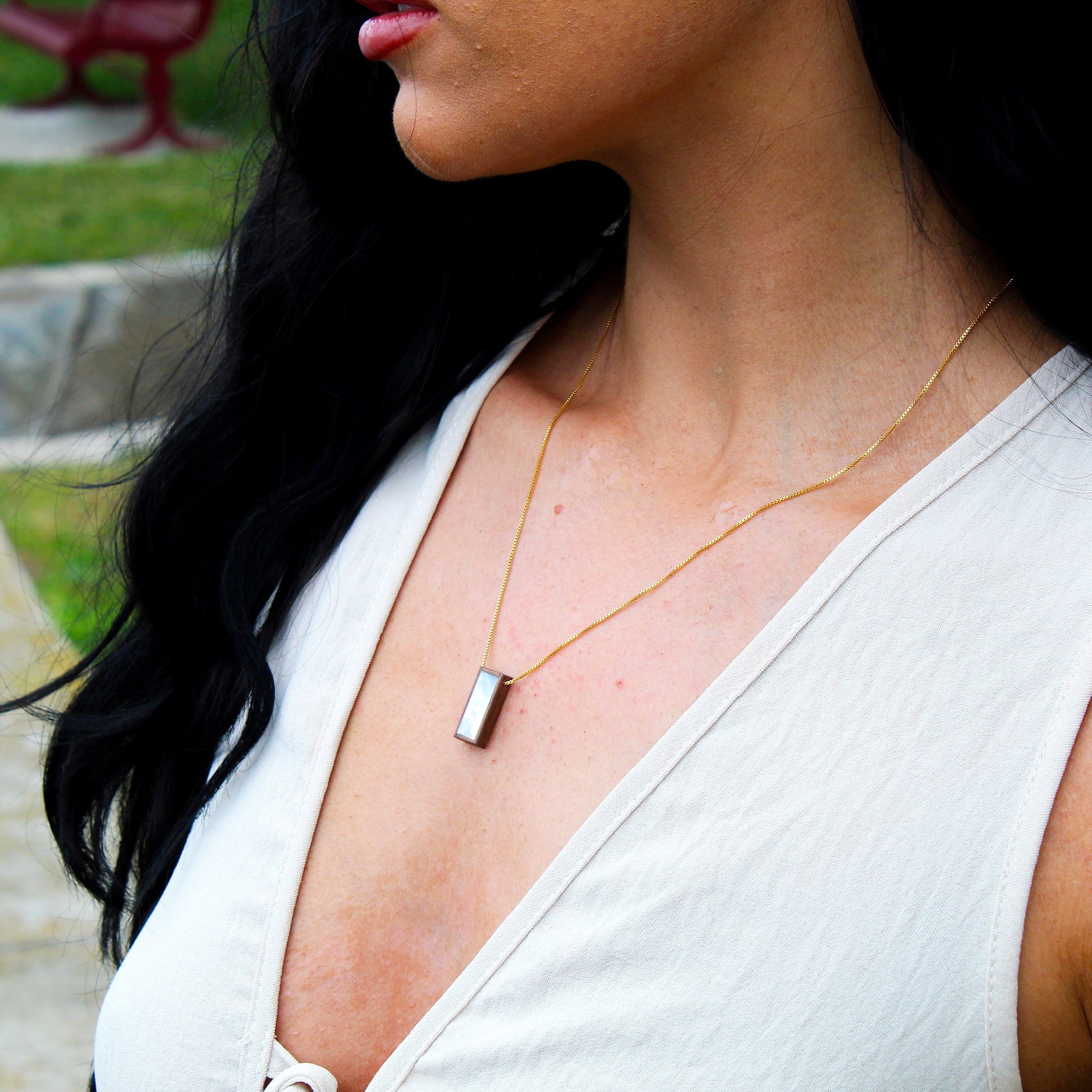 Woman wearing a necklace with a blurred outdoor background