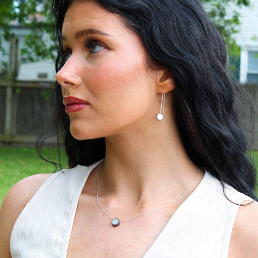 Woman wearing earrings and a necklace outdoors with a blurred background