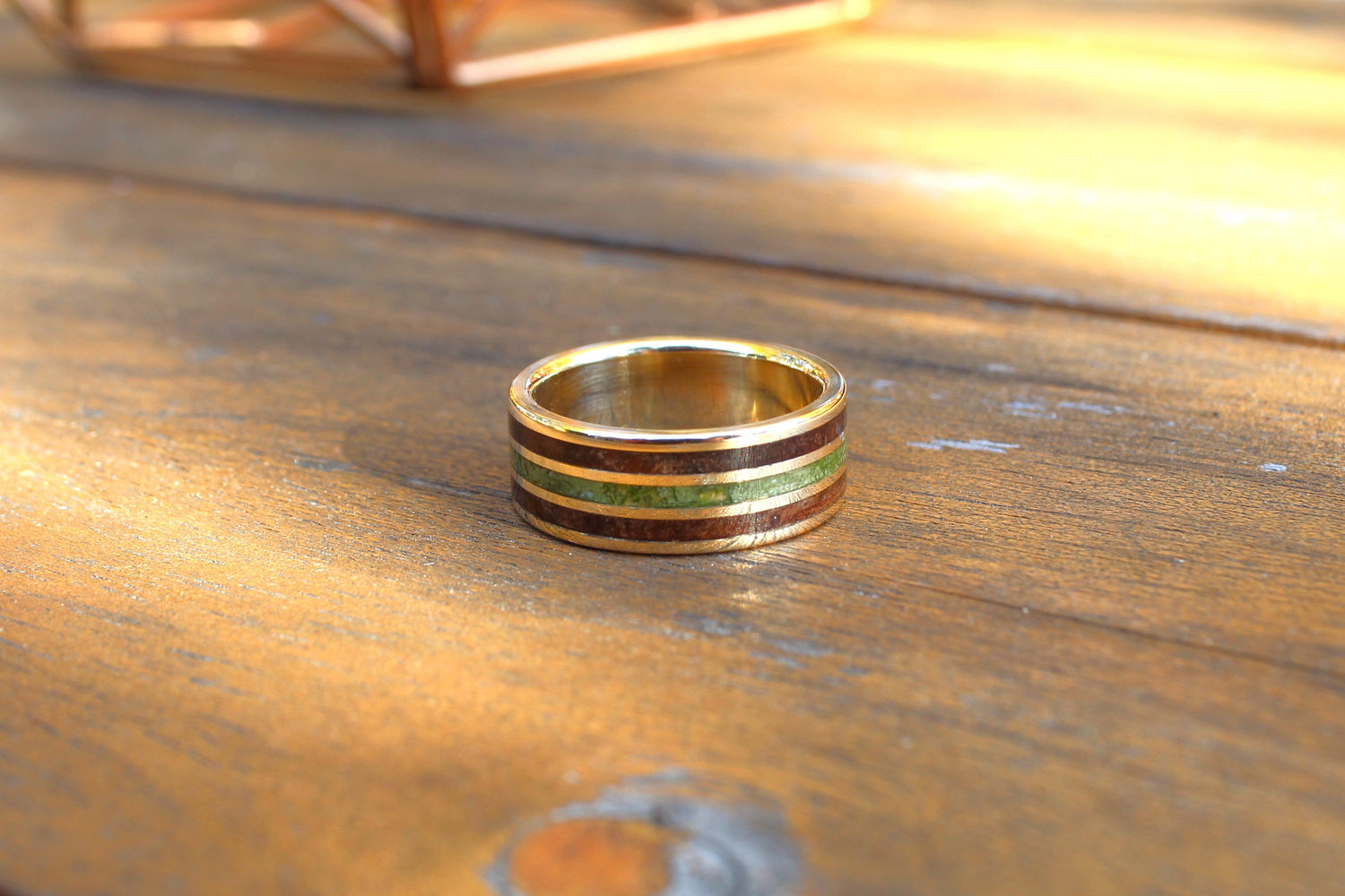 Gold ring with green inlay on a wooden surface