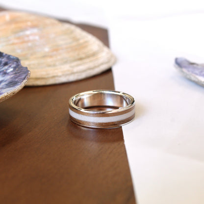 Silver ring on a wooden surface with shells in the background