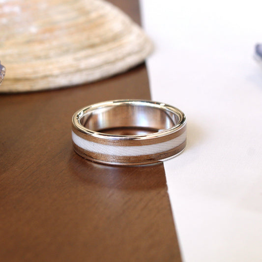 Silver ring on a wooden surface with shells in the background