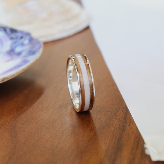 Silver ring with gold accents on a wooden surface