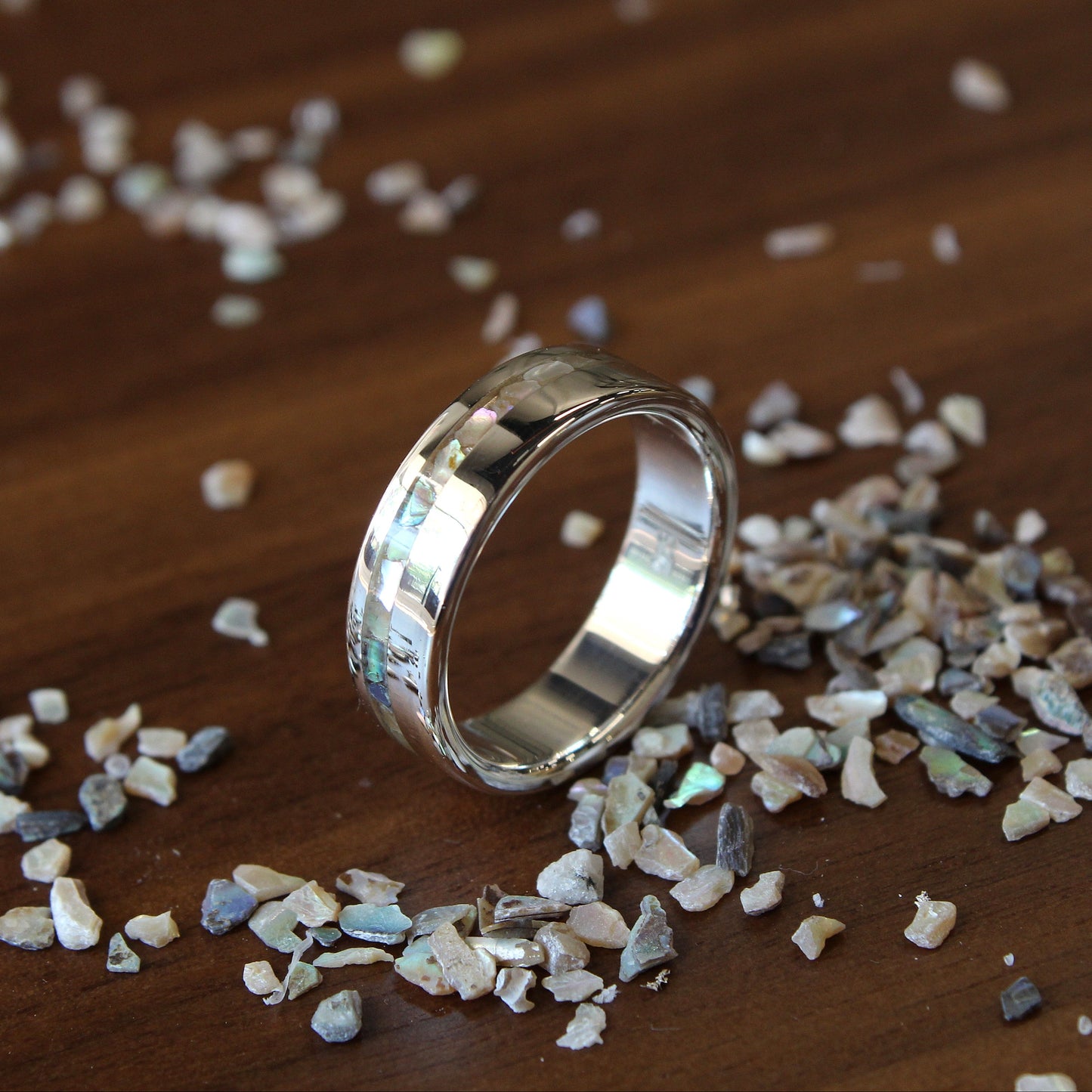 Silver ring on a wooden surface with small stones