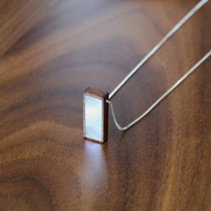 Rectangular pendant on a chain on a wooden surface