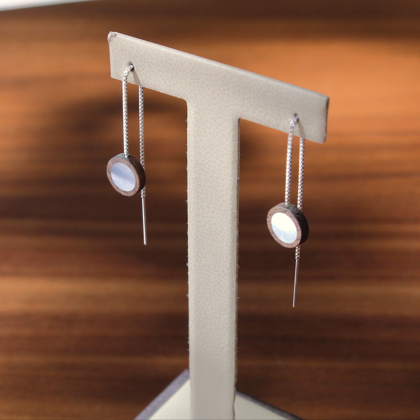 Pair of earrings on a stand against a wooden background