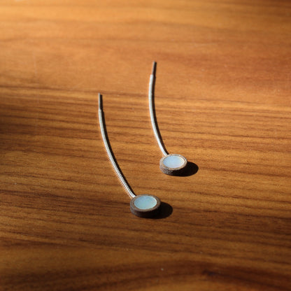 Two mother of pearl earrings on a wooden surface